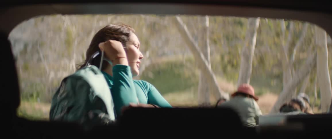 A woman smiles as she takes her backpack out of her vehicle