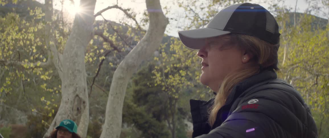 Closeup of a woman talking with the group in the midst of a forest