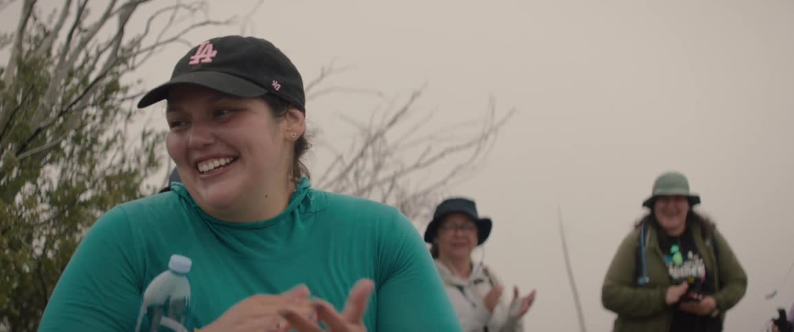 A group of women smile and clap after completing an uphill hike