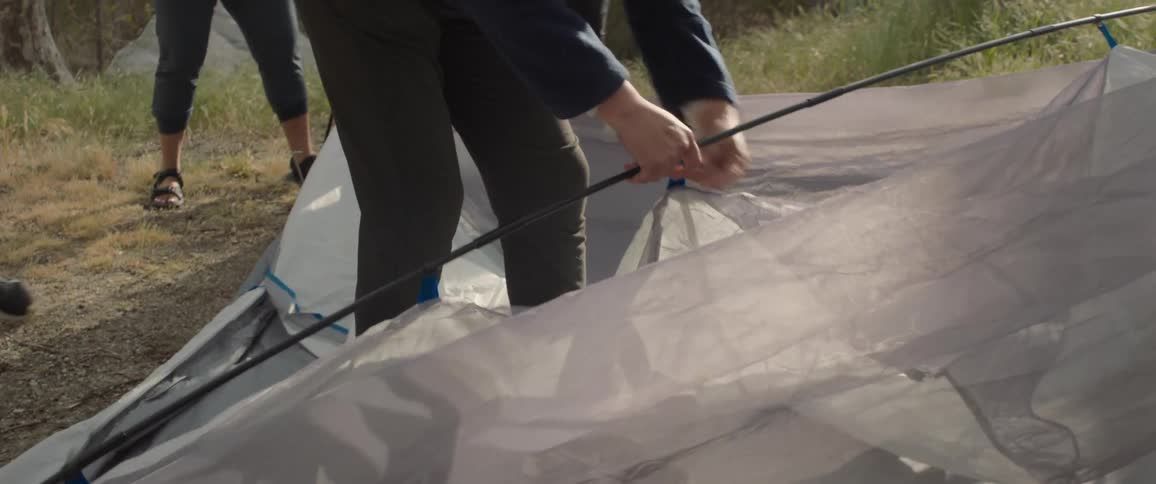 Campers set up tent at campsite near woods