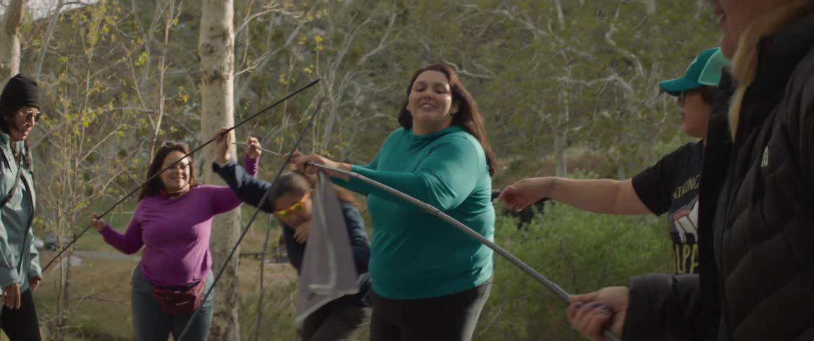 Small group of people assemble tent poles in the forest