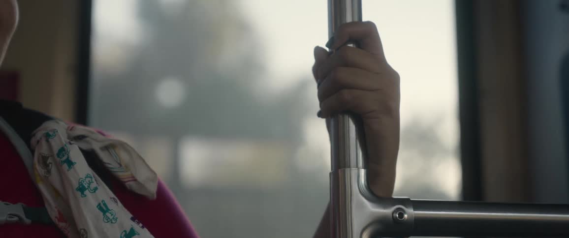 Closeup of a womans arm leaning on a pole inside public transportation
