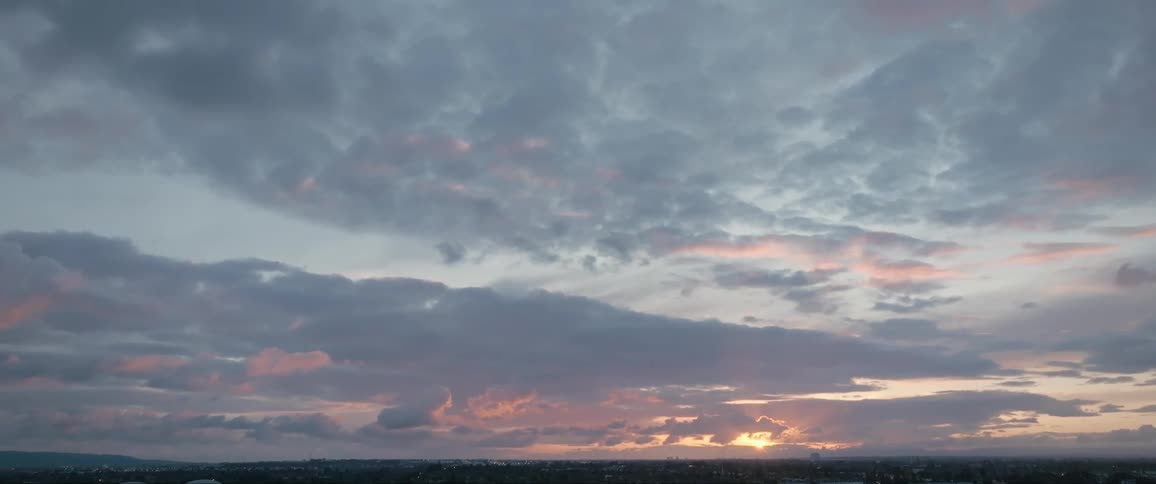 Sun shines from red horizon on a cloudy summer day