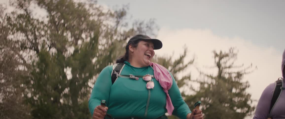 Friends walking with hiking gear in the mountains chatting and smiling