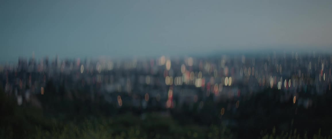 Woman on a hill overlooking a city picking up her hiking gear and walking