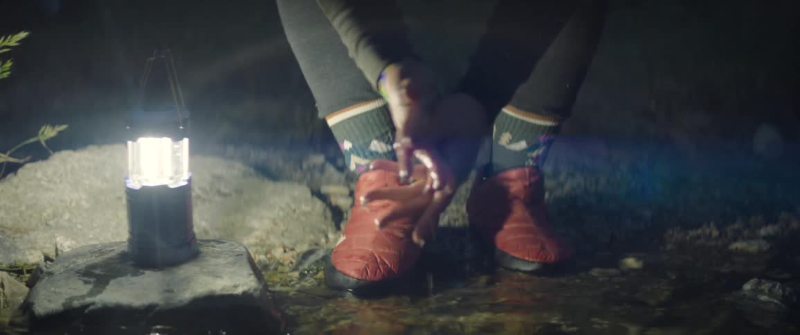 Man uses a portable electric lantern while washing his hands in a stream at night