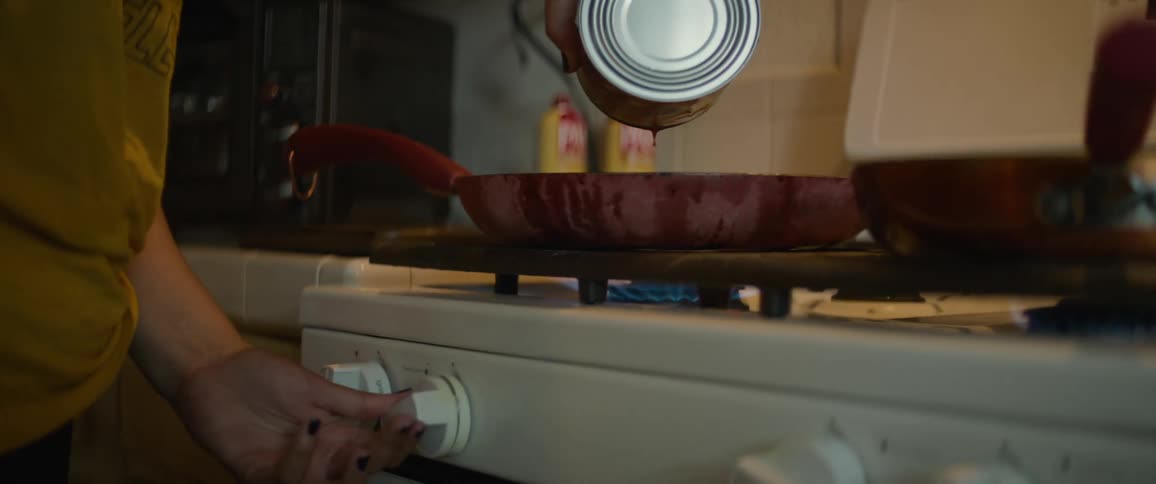 Closeup of a woman pouring tomato sauce into a frying pan on the stove