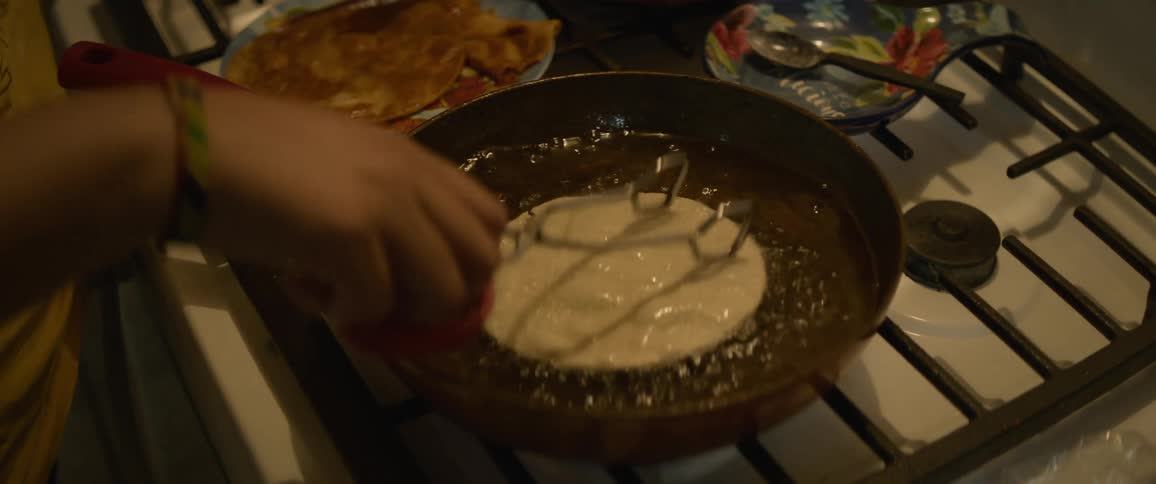 Person fries tortillas in pan on stove