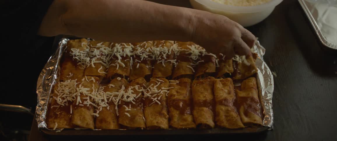 A person adding grated cheese to a meal