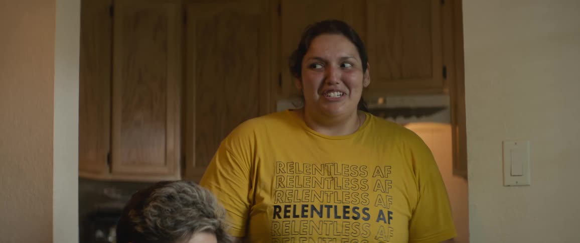 A woman standing and another sitting down talk to each other smiling and laughing