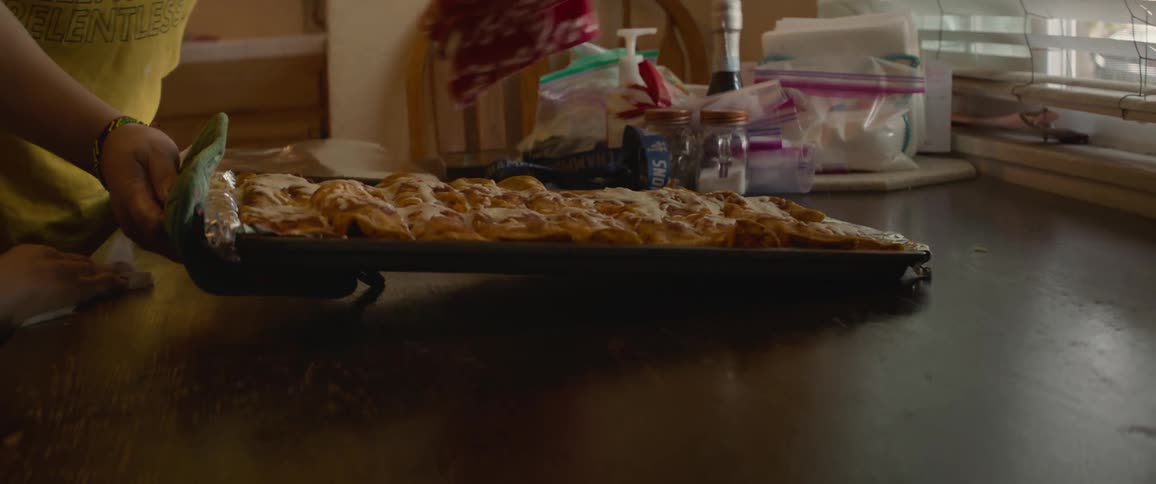 Person places tray of food on table near window indoors