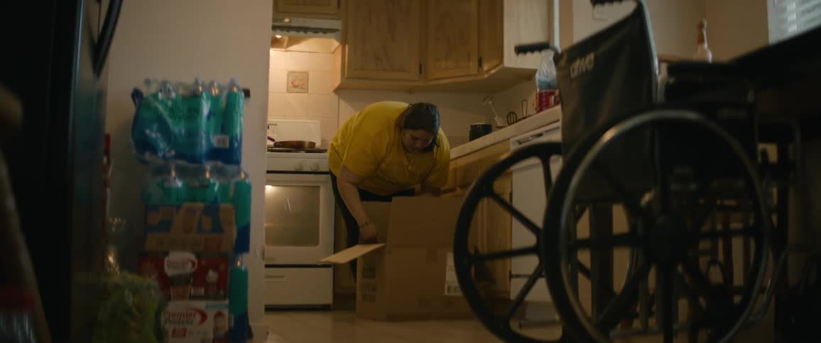 Woman closes cardboard box sitting on floor in kitchen