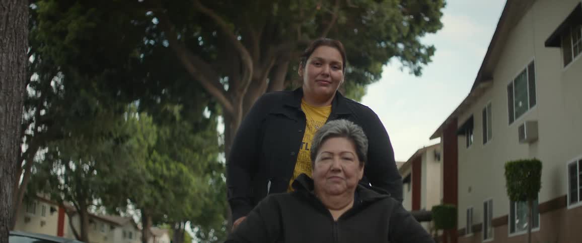 Portrait of a woman smiling behind an elderly lady in a wheelchair