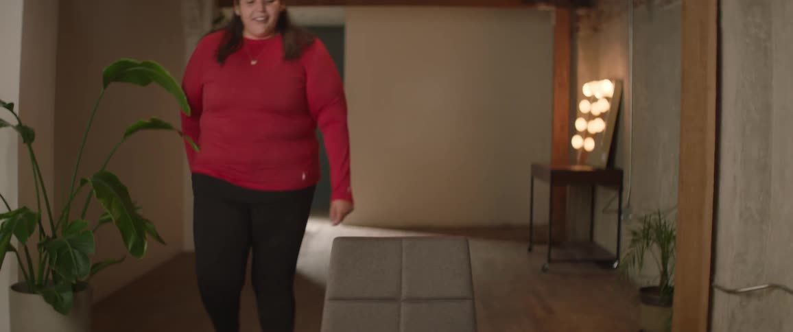 Woman entering a room and sitting in a chair in front of the camera