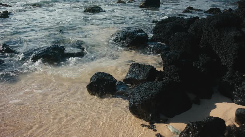 Waves crash on the black rocks on the shore