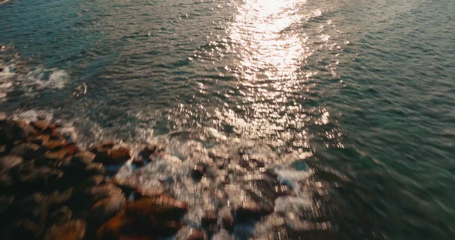 Flying Over Waves Reflecting the Morning Sun