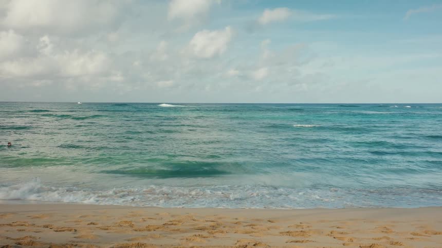 A beach with small waves breaking on the shore next to the sand