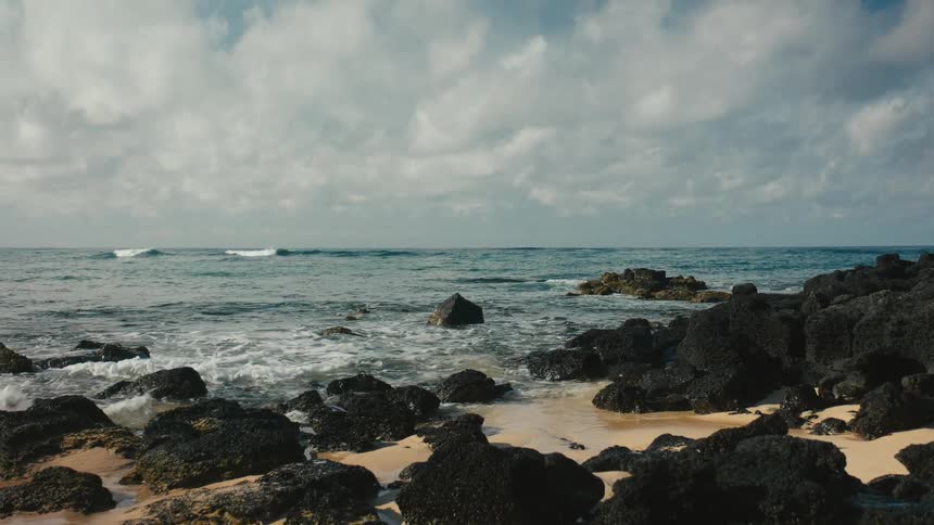 A rocky beach with a calm sea on a cloudy day