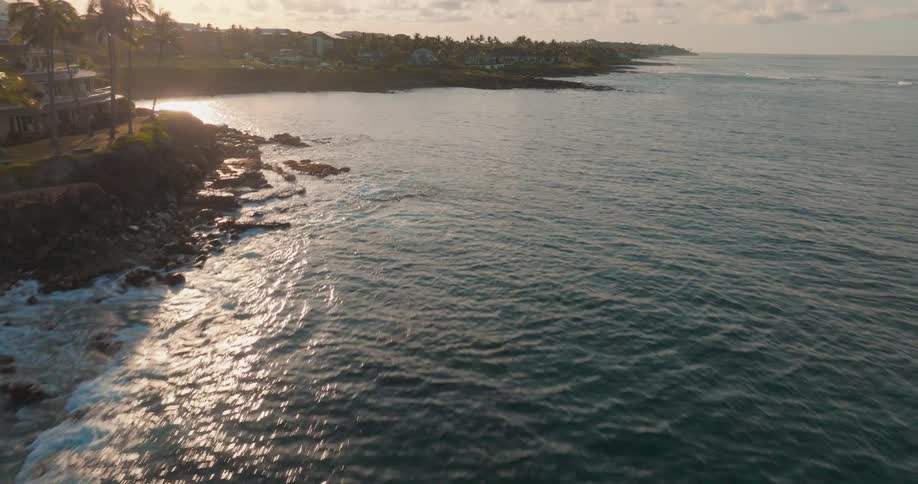 Aerial view of the sea surface and coastal area with constructions next to the shoreline during dusk or dawn