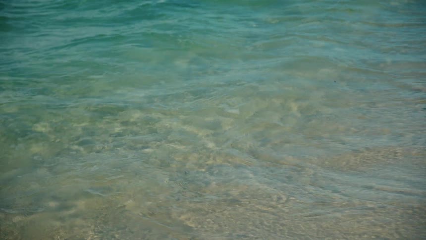 Small waves crashing on the shore of a beach and the water is crystal clear