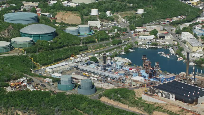 Aerial panorama of an industry with drums around it by the edge of a lake