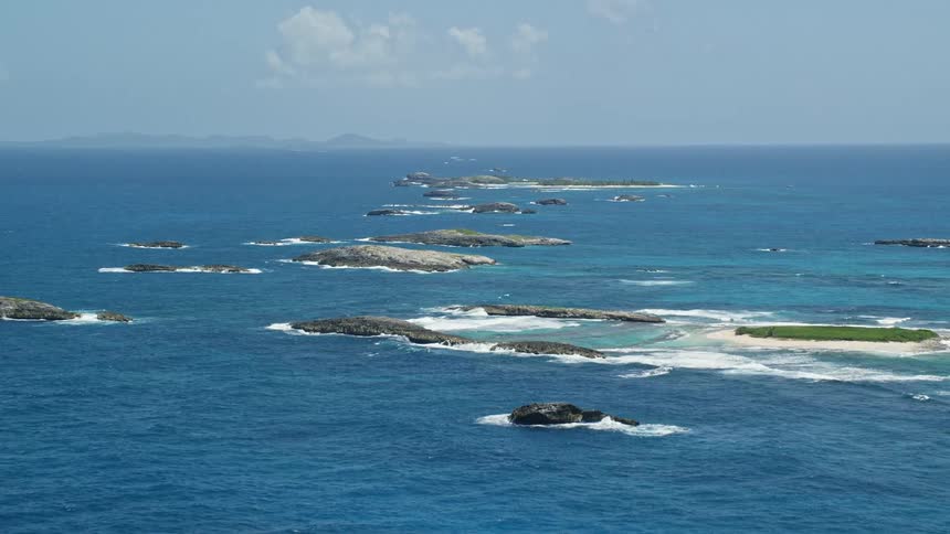 Waves crash against the row of small empty islands