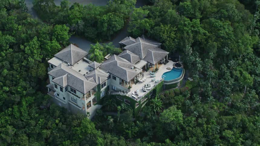 Aerial view of a mansion with a pool in the midst of a forest