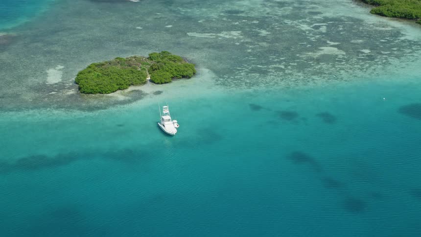 Some white boats in a region with crystal clear water and small islands with green trees some