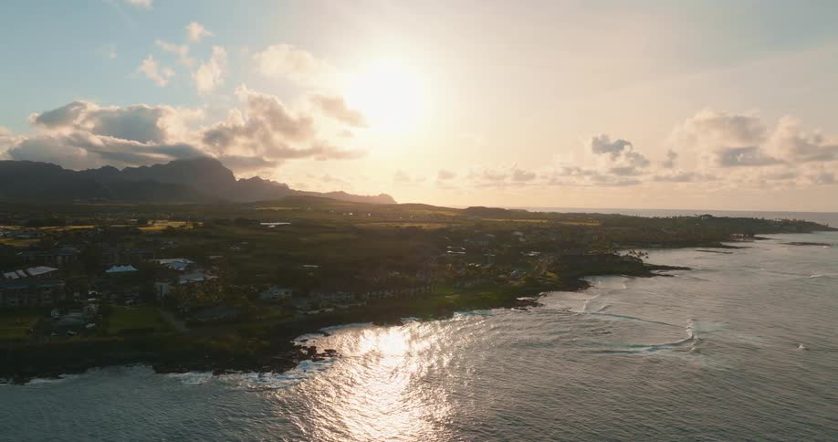 A city facing the sea that has some waves crashing and the sunlight is strong