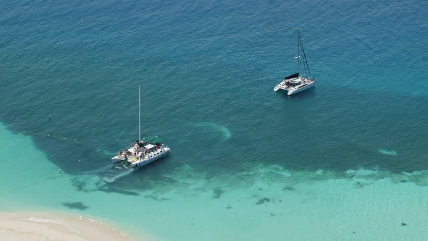 Two sailboats on a clear tropical ocean