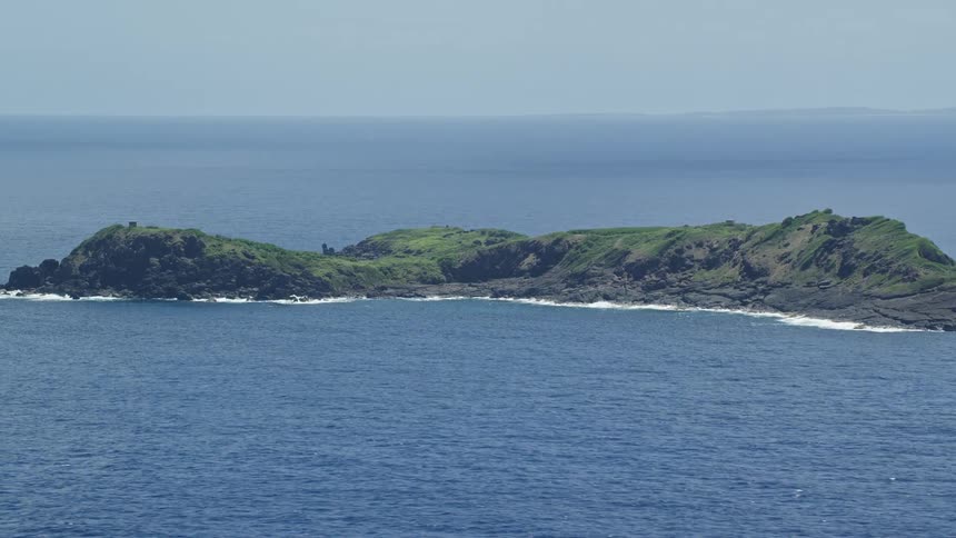 Aerial view green island in the middle of ocean on cloudless day