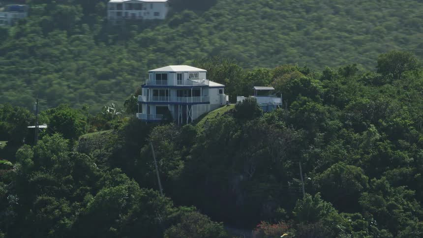 Mist covers houses sitting on forested mountains overlooking valley