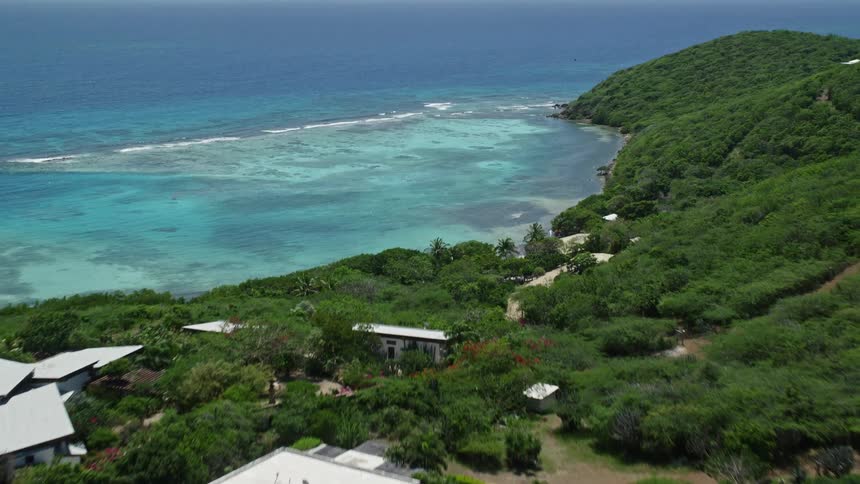 Aerial view of beachfront homes near blue harbor and green hill