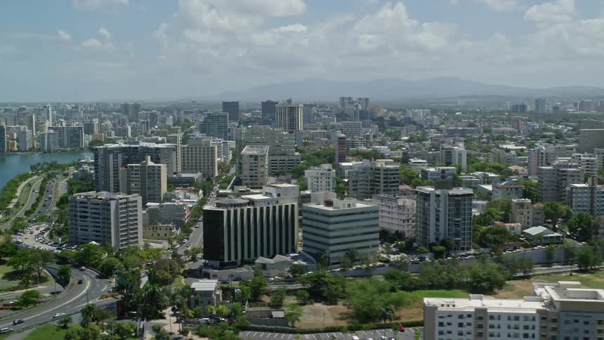 Aerial view of buildings surrounded by roads and trees on a metropolitan area next to the coast during day time