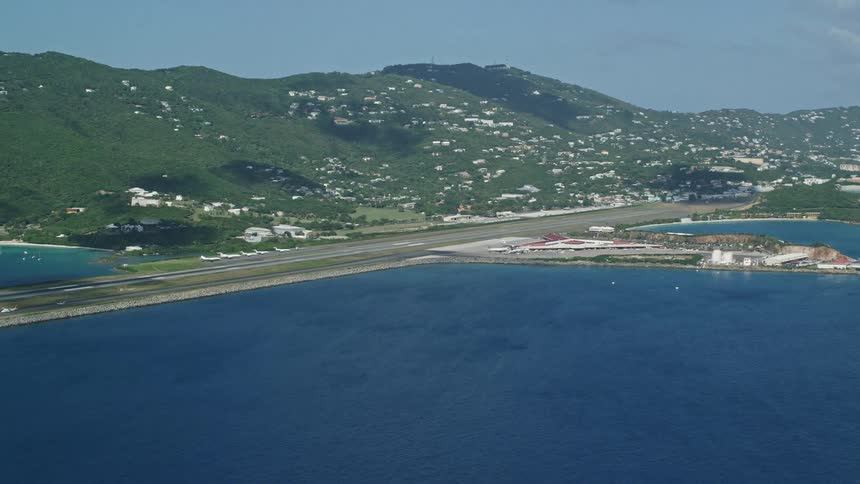 Aerial panorama of a city nestled amidst mountains facing a blue sea