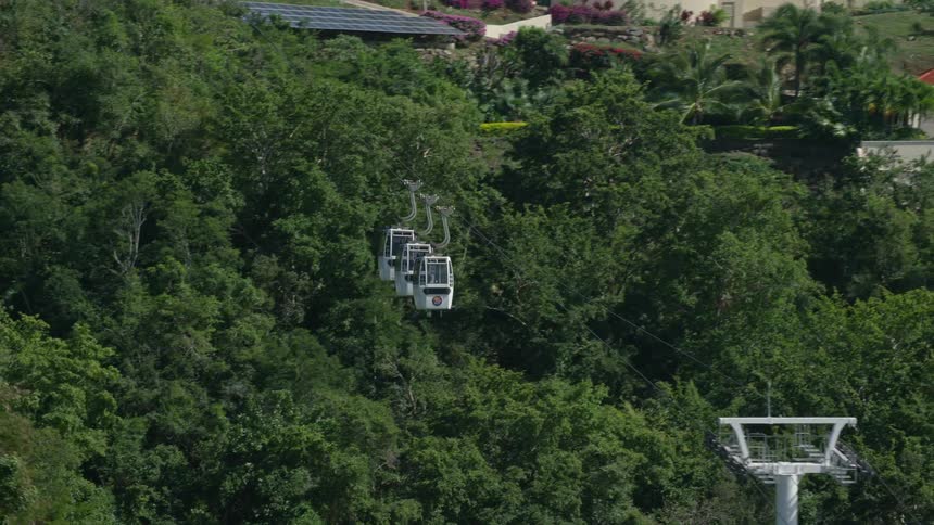 View of cable cars in motion amidst nature and hills with residential houses