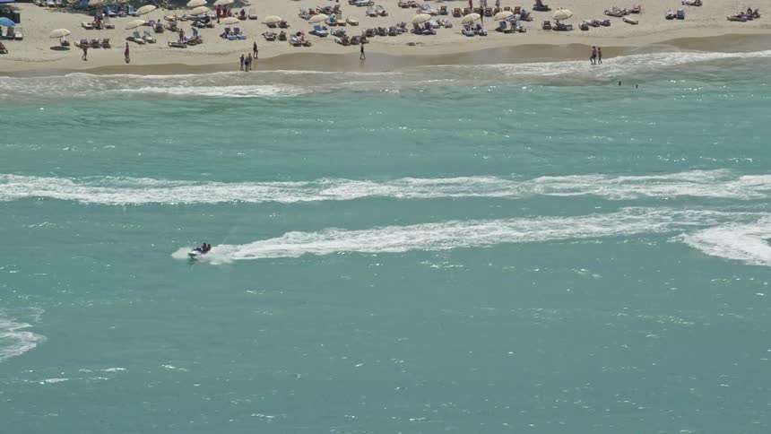 Aerial panorama of jet skis in the midst of a turquoise blue beach