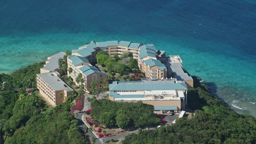 Aerial view of a resort on a hill by the turquoise blue beach