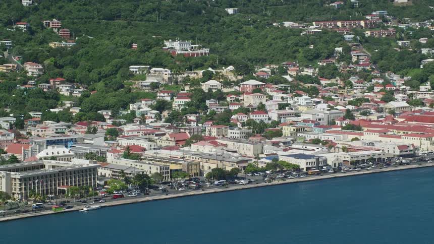 Two jet skis passing by the sea and in front of a land with many buildings and houses