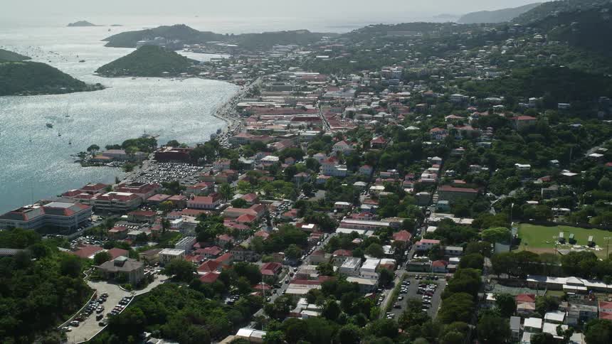 Aerial view of a suburban area next to the coast surrounded by hills and vegetation during day time