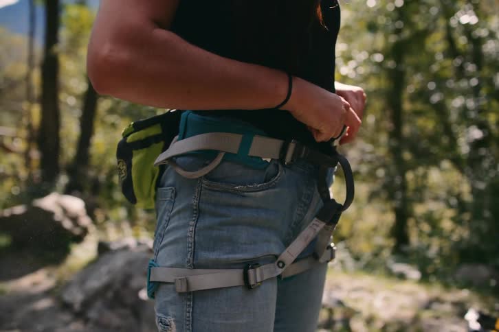 Person wearing jeans straps on waist harness standing out doors
