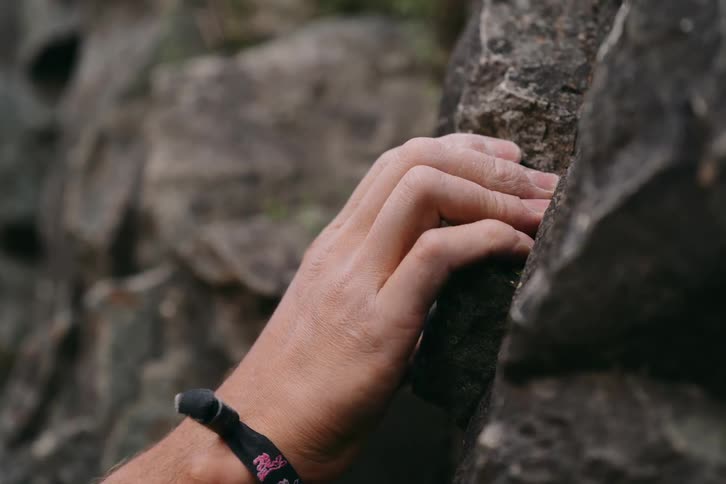 A hand grabs a hold on a rock