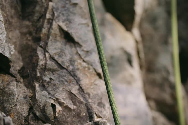 A green rope stretched across a rock with a rough surface