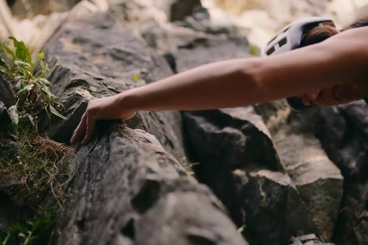 A rock climber goes up a cliff feeling for crevices to hold on to