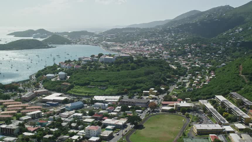 Aerial view of urban area next to the ocean to one side and mountains to the other during day time