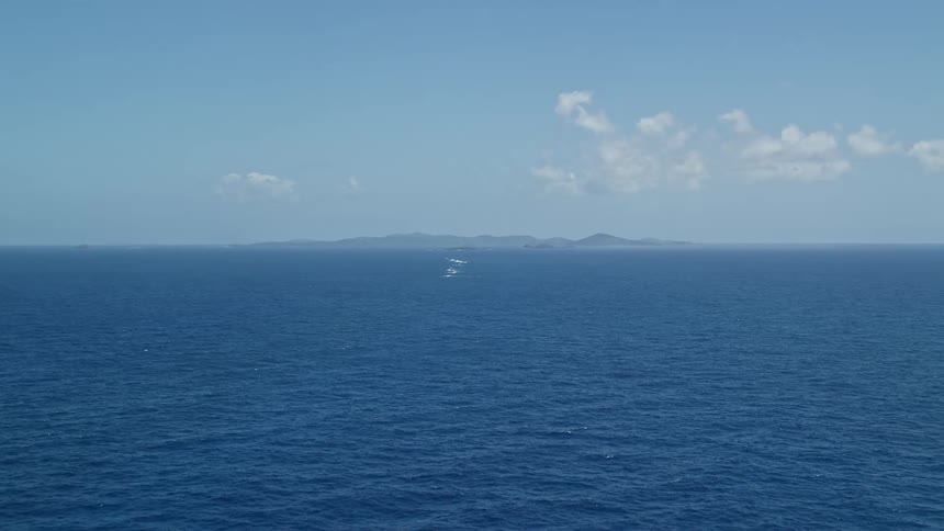 Aerial view of blue ocean island on the horizon