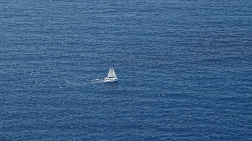 A sailing boat sailing across the ocean on a sunny day
