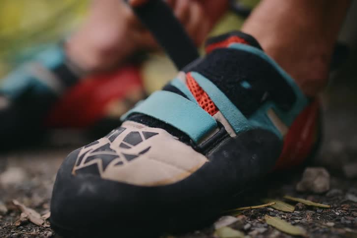 A person is tying a sneaker that is on their foot and attaching a velcro strap