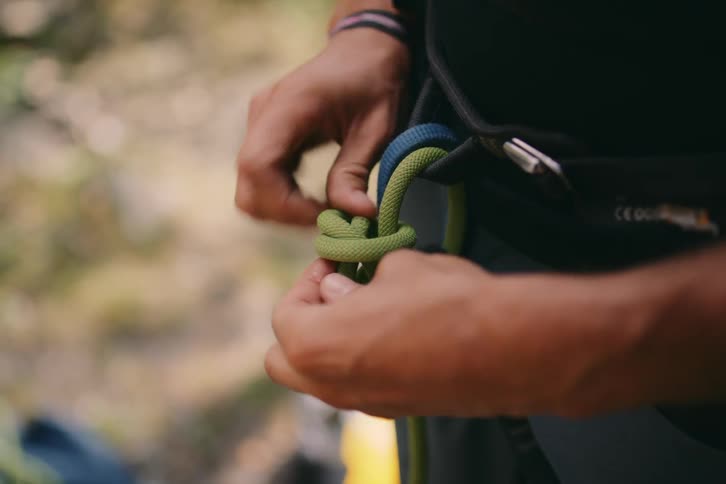 A person using their two hands to tie a rope and form a knot