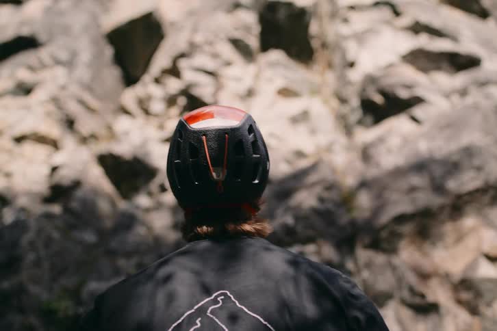 Climber wearing helmet stand in front of rock wall